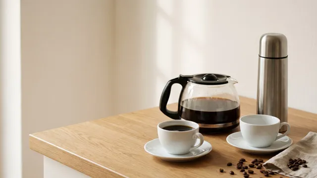 KI-generiertes Symbolbild: Glaskanne mit Filterkaffee, Thermoskanne aus Edelstahl und zwei weiße Tassen auf heller Arbeitsplatte
